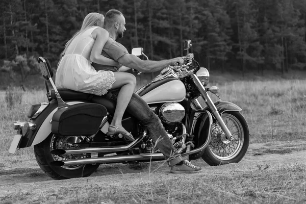 Newlyweds middle of the field on a motorcycle road. Happy couple traveling on a motorcycle. Extraordinary life. Black-and-white photo for social and posters and websites motorcycle magazines.