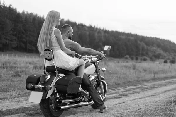 Newlyweds middle of the field on a motorcycle road. Happy couple traveling on a motorcycle. Extraordinary life. Black-and-white photo for social and posters and websites motorcycle magazines.