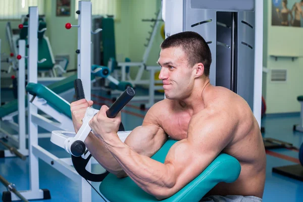Strong muscular man doing exercises in the gym.