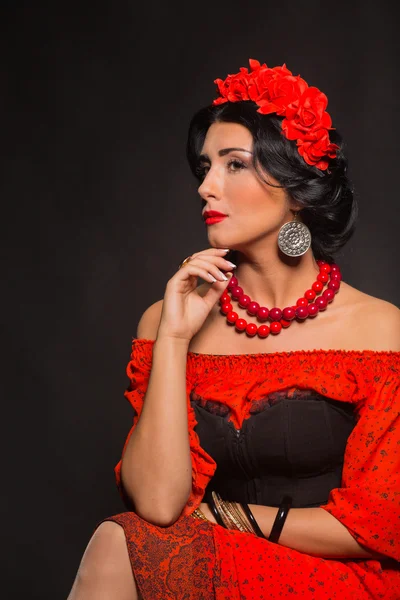 Beautiful, sexy woman in red. Beautiful image of the girl in red. Elegant wreath of red flowers, stylish jewelry, portrait of a girl.