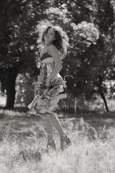 Young brunette woman in a white dress. A girl stands in the middle of pink flowers field on a sunny day. Field, flowers beauty, nature, - The concept of country vacation. Article about vacation.