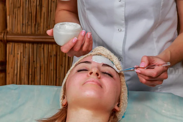 Beauty treatments for problem skin. The girl in the spa salon, applying cream.