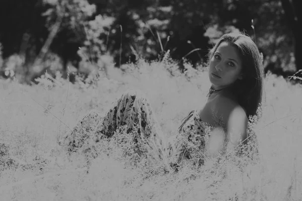 Young brunette woman in a white dress. A girl stands in the middle of pink flowers field on a sunny day. Field, flowers beauty, nature, - The concept of country vacation. Article about vacation.