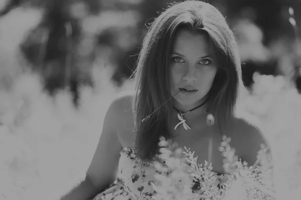 Young brunette woman in a white dress. A girl stands in the middle of pink flowers field on a sunny day. Field, flowers beauty, nature, - The concept of country vacation. Article about vacation.