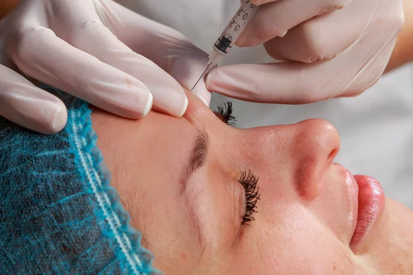 Cosmetic injection in the spa salon. Beautician makes injection into the patient\'s face.