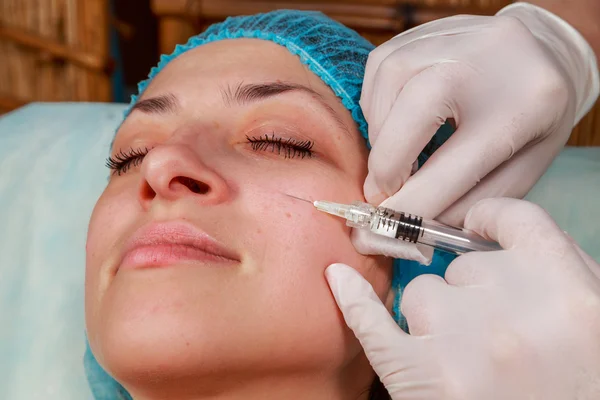 Cosmetic injection in the spa salon. Beautician makes injection into the patient's face. Beauty injections, mesotherapy, revitalization, cosmetic medicine injection - the concept of rejuvenation.