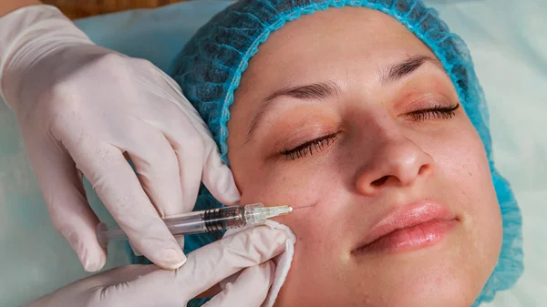 Cosmetic injection in the spa salon. Beautician makes injection into the patient\'s face.
