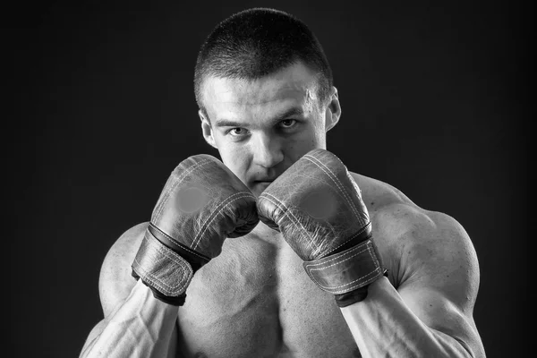 The man in boxing gloves. Young Boxer fighter over black background. Boxing man ready to fight. Boxing, workout, muscle, strength, power - the concept of strength training and boxing