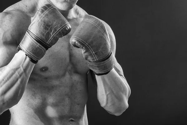 The man in boxing gloves. Young Boxer fighter over black background. Boxing man ready to fight. Boxing, workout, muscle, strength, power - the concept of strength training and boxing