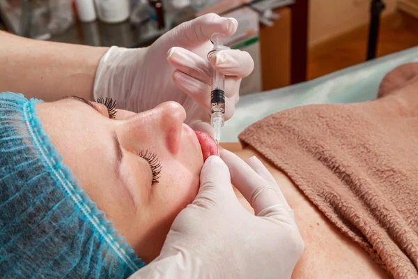 Cosmetic injection in the spa salon. Beautician makes injection into the patient\'s face. Beauty injections, mesotherapy, revitalization, cosmetic medicine injection - the concept of rejuvenation.