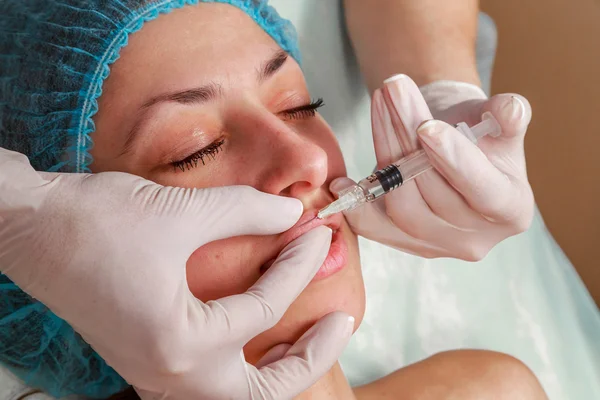 Cosmetic injection in the spa salon. Beautician makes injection into the patient\'s face. Beauty injections, mesotherapy, revitalization, cosmetic medicine injection - the concept of rejuvenation.