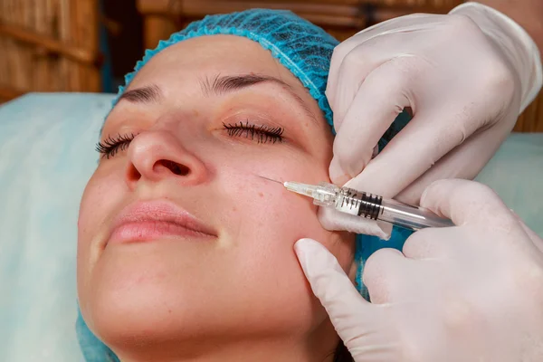Cosmetic injection in the spa salon. Beautician makes injection into the patient\'s face. Beauty injections, mesotherapy, revitalization, cosmetic medicine injection - the concept of rejuvenation.