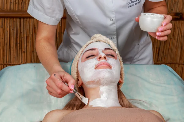 Applying the mask to the face of a young girl. Facial skin at spa salon