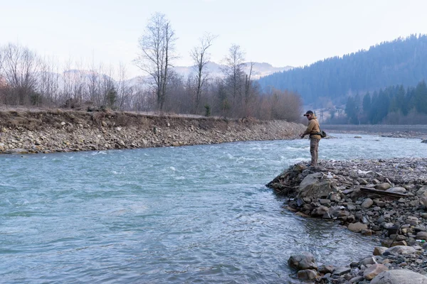 Fisherman on the shore of a mountain river