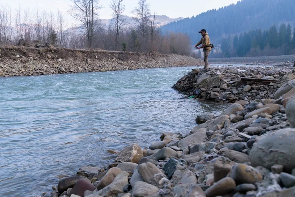 Fisherman on the shore of a mountain river
