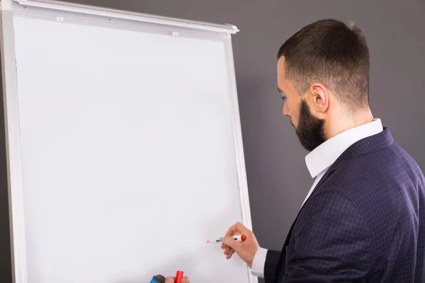 Business coach writes on the blackboard for the markers