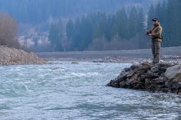 Fisherman on the shore of a mountain river