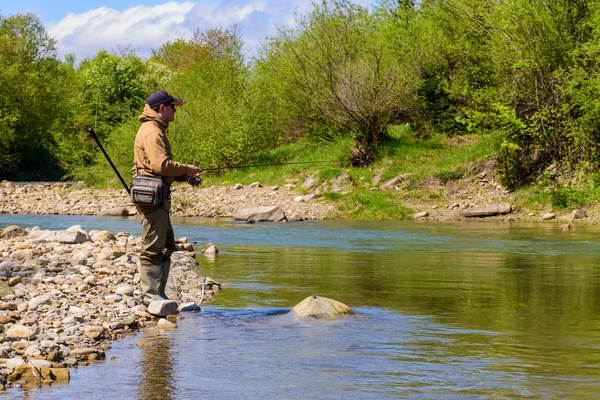 Fishing on the mountain river. Fisherman on the shore. Summer Ac