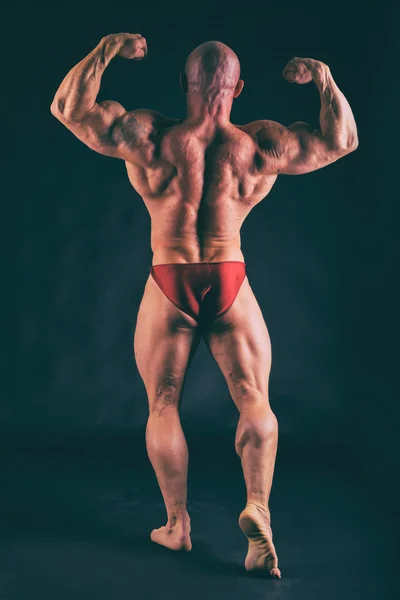 Muscular, relief body bodybuilder on a black background. Black a