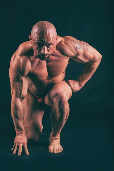 Muscular, relief body bodybuilder on a black background. Black a