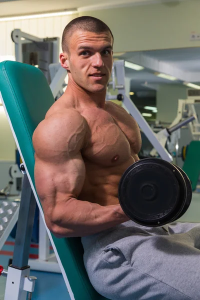 Bodybuilder with dumbbells in fitness club