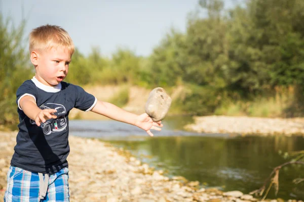 Boy throwing stones to the water