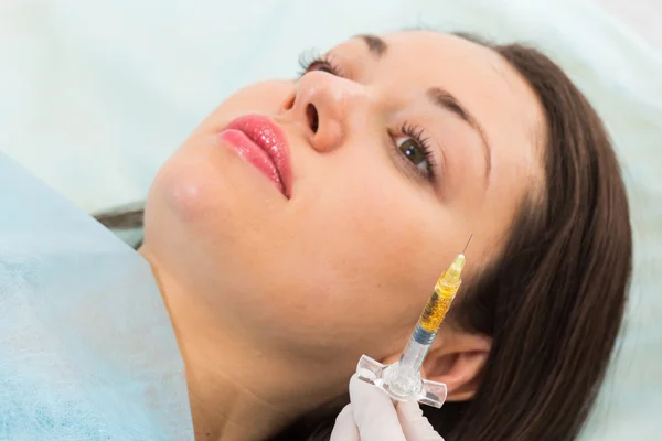 Beautician makes injection into the patient's face