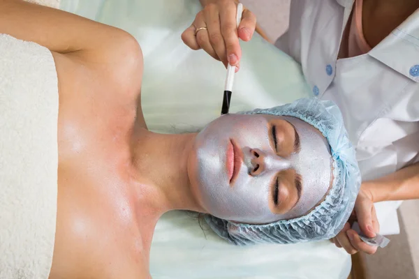 Young woman receiving facial mask