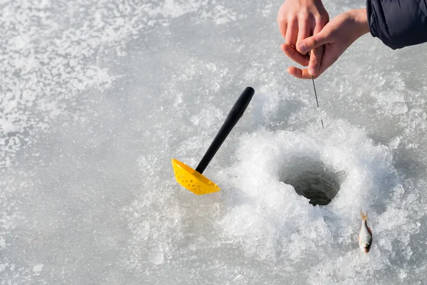Fisherman on ice fishing from the well