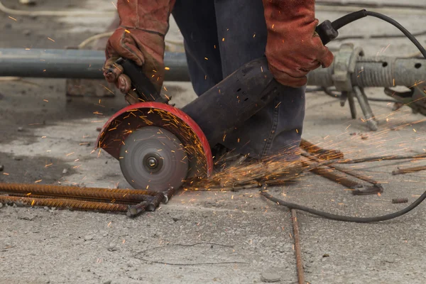 Construction worker cuts metal grinder