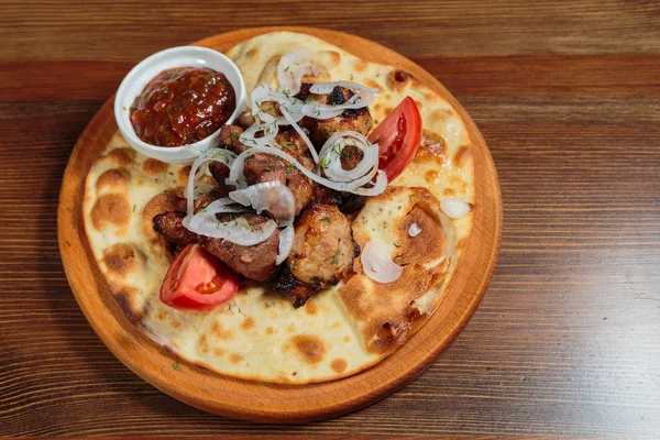 Appetizing roasted meat with vegetables on pita bread