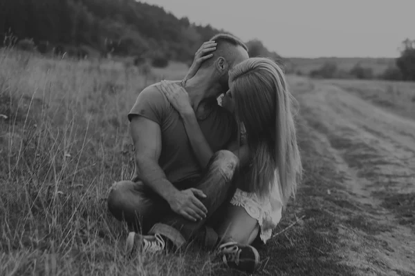 Muscular man with a beautiful woman on a motorcycle middle of a field road