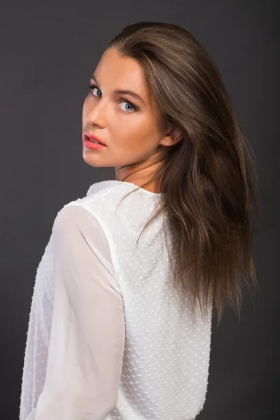 Stylishly dressed young business lady. The image of a beautiful young business lady. Girl in black pants and a white shirt on a dark background. Photo for fashion and social magazines, websites.