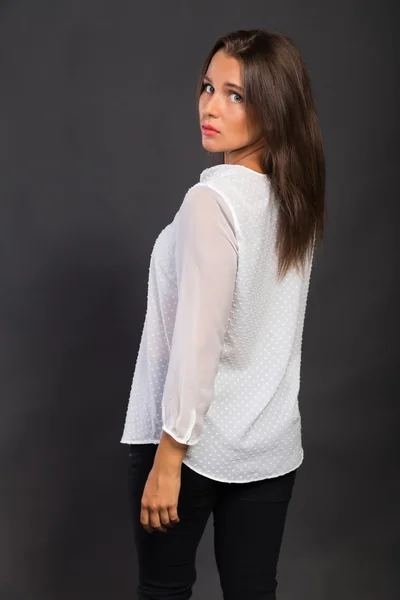 Stylishly dressed young business lady. The image of a beautiful young business lady. Girl in black pants and a white shirt on a dark background. Photo for fashion and social magazines, websites.