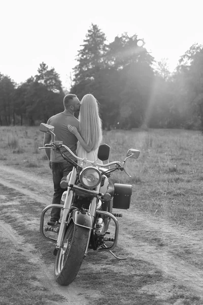 Black and white photo biker couple on a motorcycle in the field.