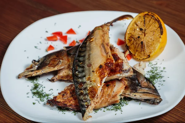 Smoked mackerel with vegetables grilled on a white plate.