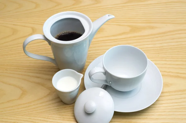 Coffee in jug with white coffee cup and milk on the wood table