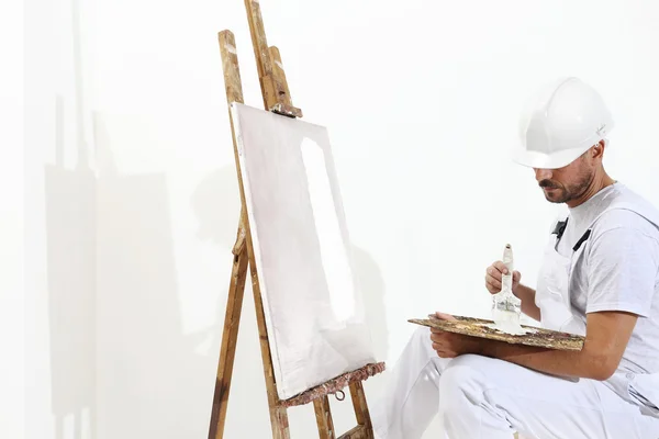 Painter man with canvas on easel, palette and brush, isolated