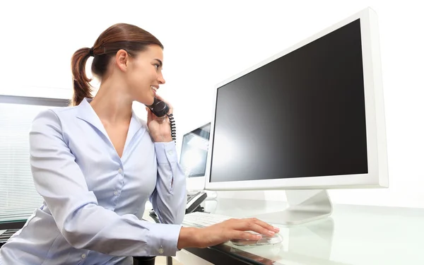 Smiling woman in office at desk in front of computer screen