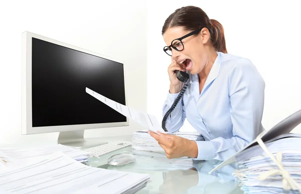 Angry woman at phone in office desk with computer and documents