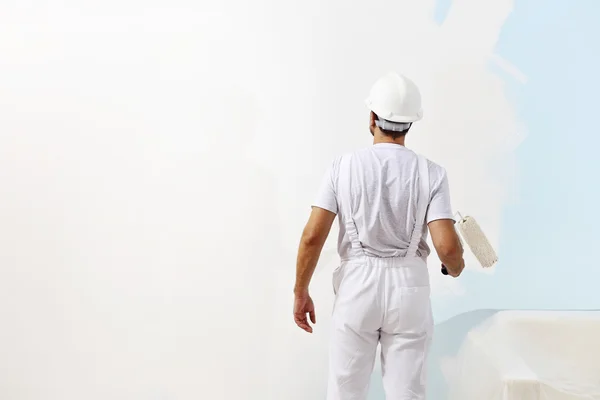 Painter man at work with a paint roller, wall painting concept