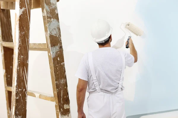 Painter man at work with a paint roller, wall painting concept