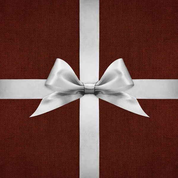 Shiny silver satin ribbon bow on red background