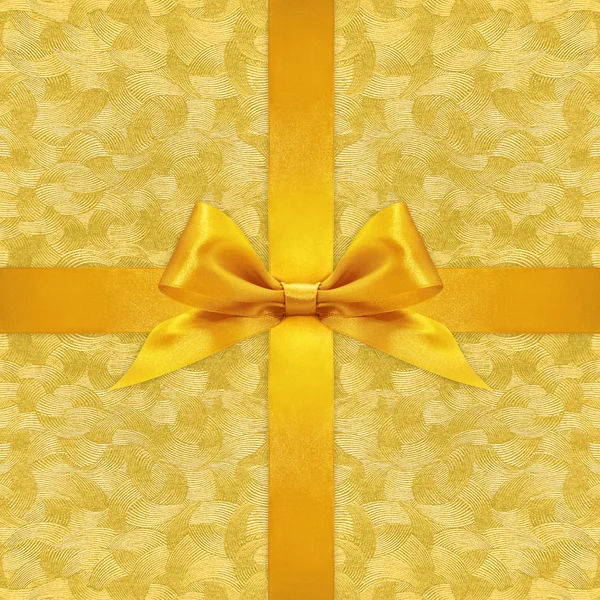 Shiny golden satin ribbon bow on gold background