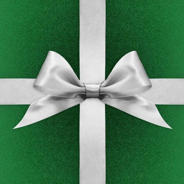 Shiny silver satin ribbon bow on green background