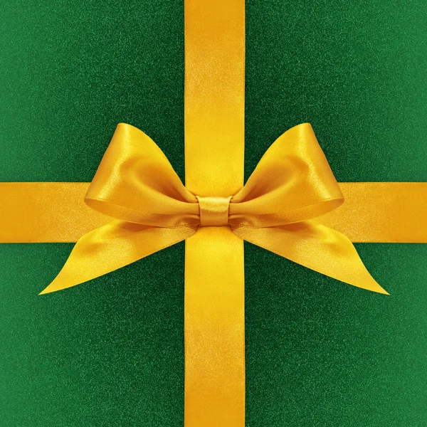 Shiny golden satin ribbon bow on green background
