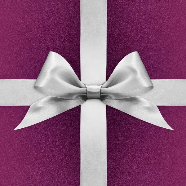 Shiny silver satin ribbon bow on purple background