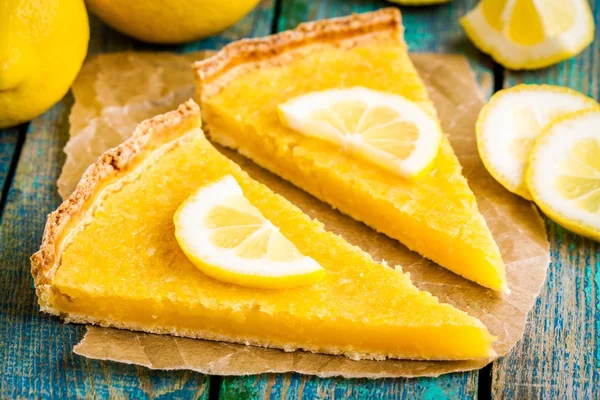 Two pieces of lemon tart with slice of lemons closeup