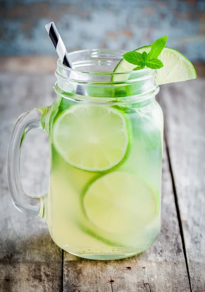 Homemade lemonade with lime, mint in a mason jar on a wooden table
