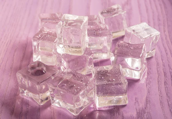 Ice cubes on purple colored  wooden background